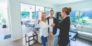 real estate agent shaking hands with couple in house