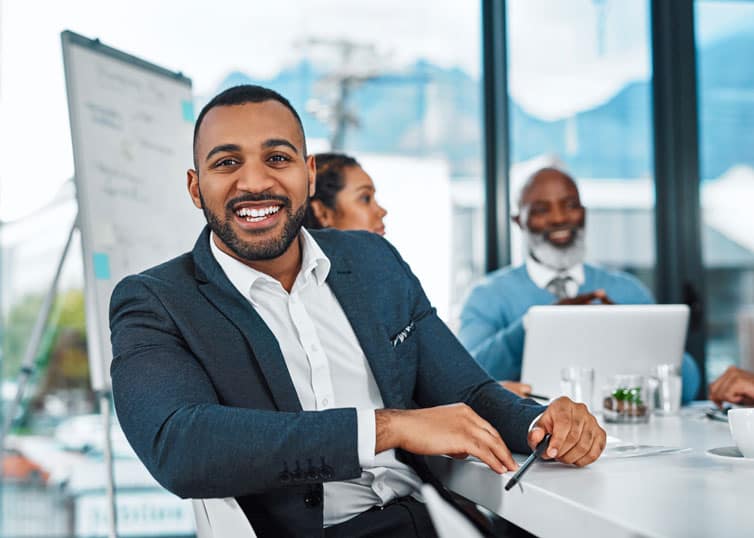 Head of real estate brokerage firm smiling as he meets with his team of brokers