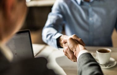 Newly licensed real estate broker shaking hands with a managing broker