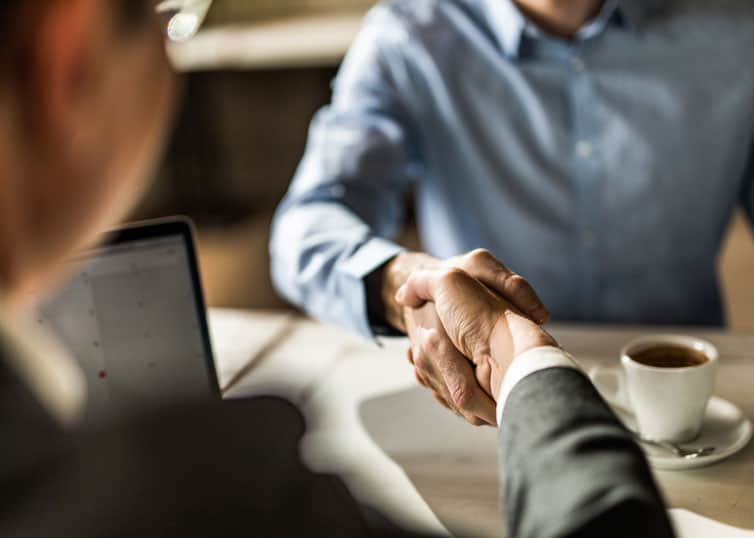 Newly licensed real estate broker shaking hands with a managing broker