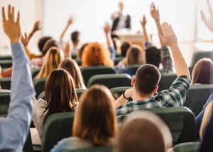 Classroom full of real estate pre-licencees raising their hands to answer a question