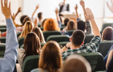 Classroom full of real estate pre-licencees raising their hands to answer a question