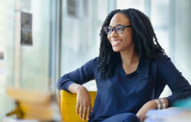 Real estate broker gazing out her office window with a big smile