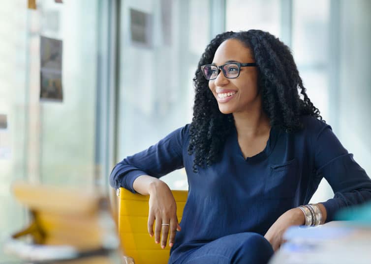 Real estate broker gazing out her office window with a big smile