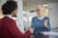 Mature gray haired woman and young businessman handshaking and greeting at meeting in office