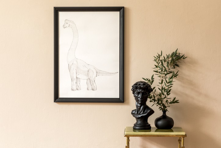 Minimalistic composition of living room interior with black mock up poster frame, green marble coffee table, flower in vase and sculpture. Beige wall. Stylish home decor. Template.