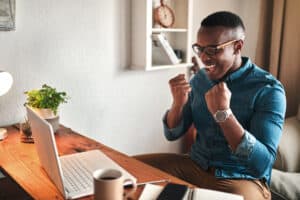 Cropped shot of a handsome young businessman sitting alone in his home office and feeling excited while using his laptop