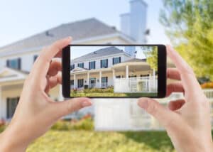 Woman's hands holding mobile phone to capture exterior real estate photos