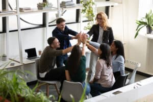 Diverse real estate staff giving high five demonstrating supportive brokerage culture