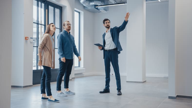 North Carolina real estate broker showing a new empty office space to young male and female business owners