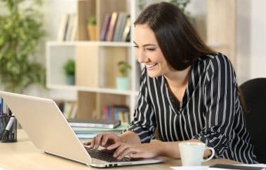 Happy woman typing on laptop, taking online real estate classes from home