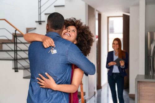 Loving couple buying a house and celebrating with a hug