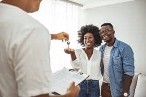 Handsome realtor is giving key to the new apartment to happy young couple.