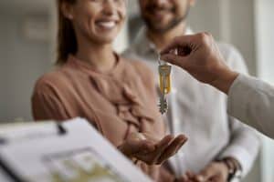 Close-up of real estate agent giving new house keys to first-time homebuyers