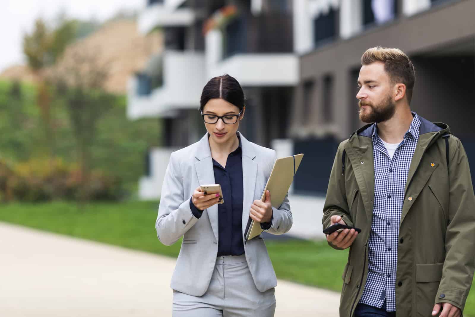 A female real estate professional meeting with her client, checking her phone, multitasking