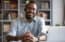 African man wearing headphones sits at desk smiling, completing professional development course online