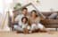 North Carolina homebuyers, parents with child smiling and roof mockup over heads while sitting on floor in cozy living room, relocation concept