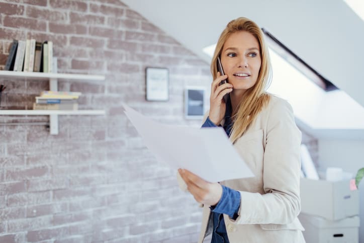 Busy real estate broker talking on smart phone in her office