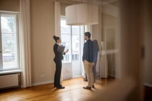 Female real estate broker shows empty home to man and woman