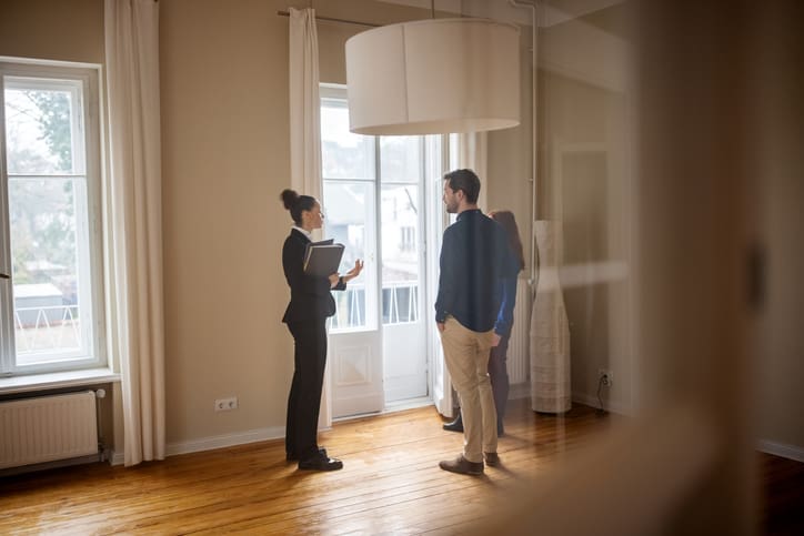 Female real estate broker shows empty home to man and woman
