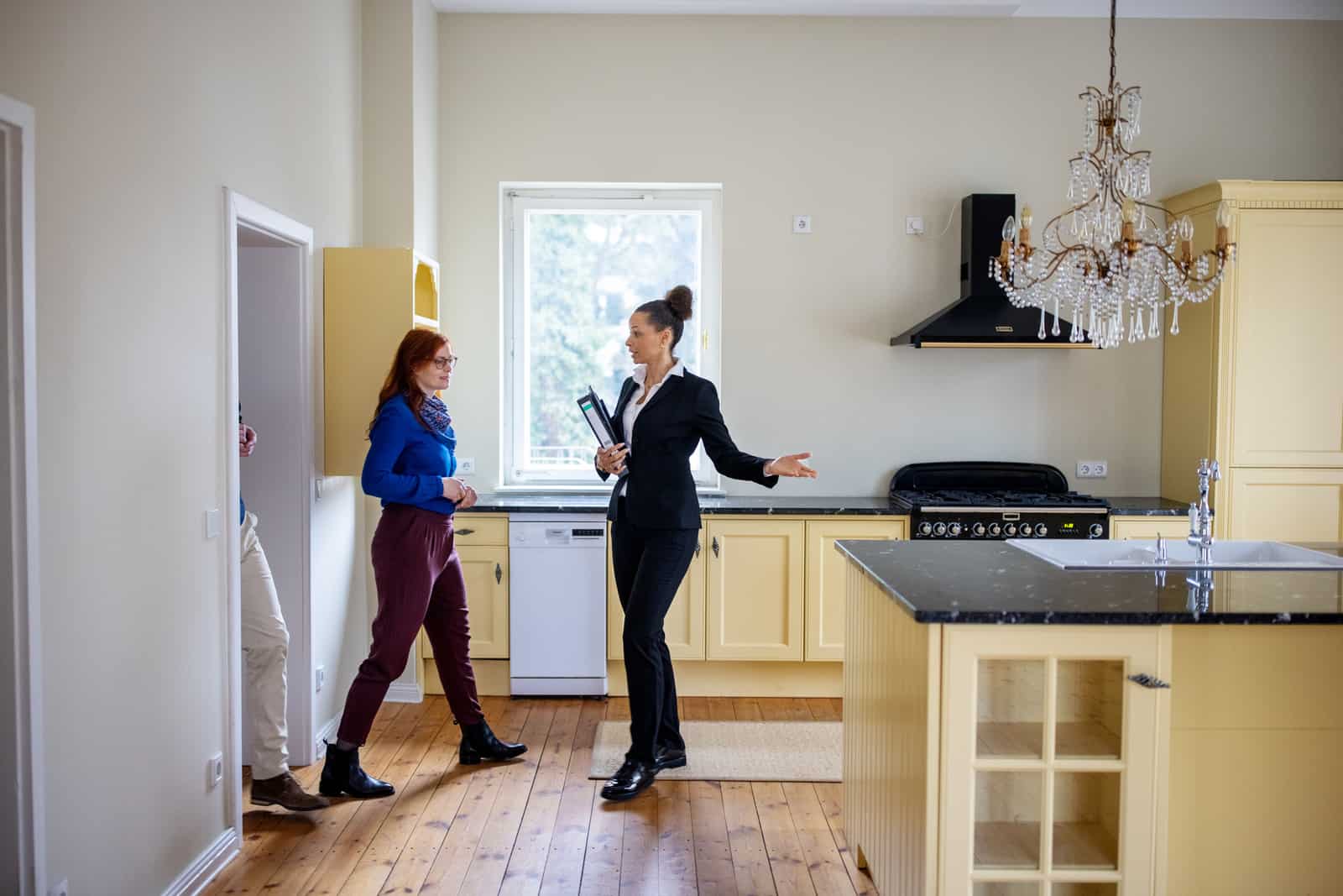 Couple entering while real estate agent showing new kitchen