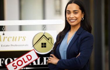 Cropped portrait of an attractive young real estate agent standing with her arms crossed next to a sold sign outside of a recently sold home