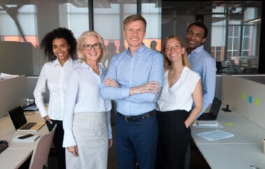 Smiling real estate team with broker-in-charge forefront posing for group picture at workplace