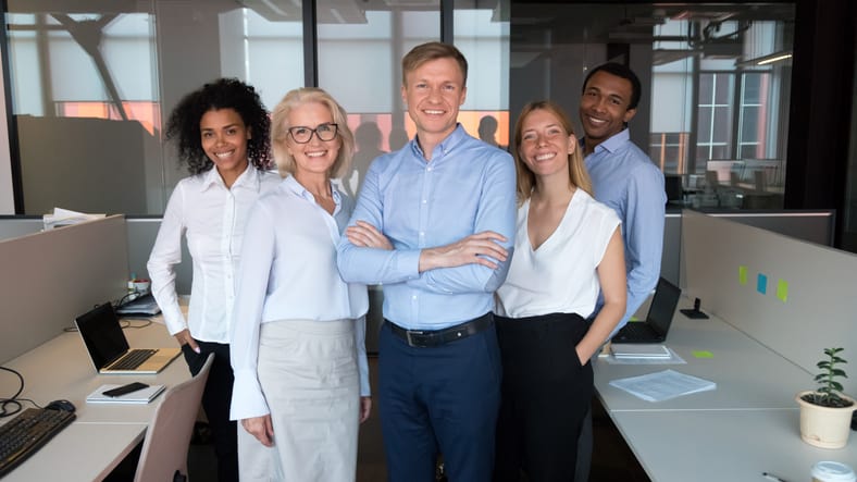 Smiling real estate team with broker-in-charge forefront posing for group picture at workplace